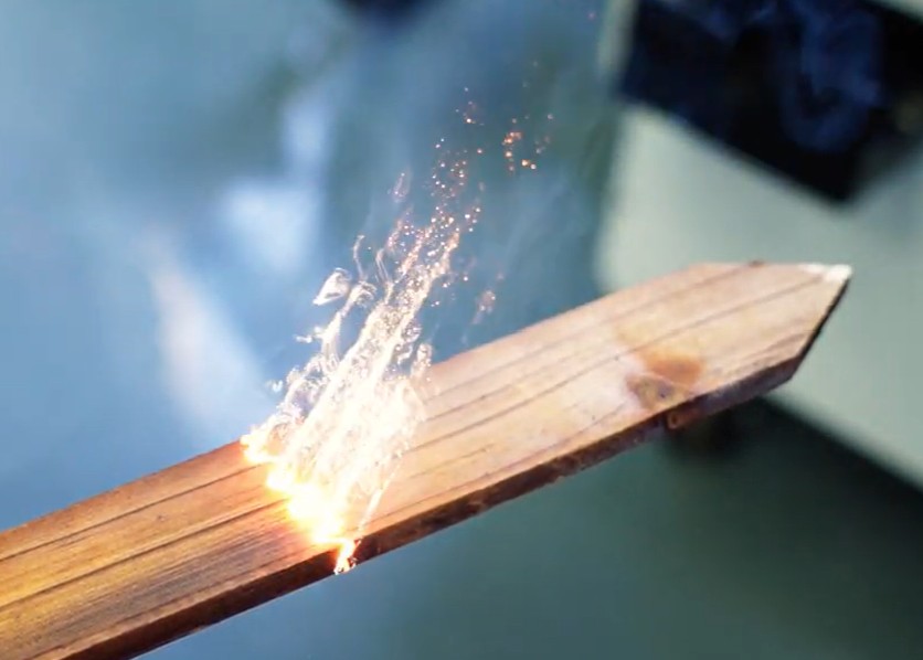 Laser beam ablating surface with sparks and smoke